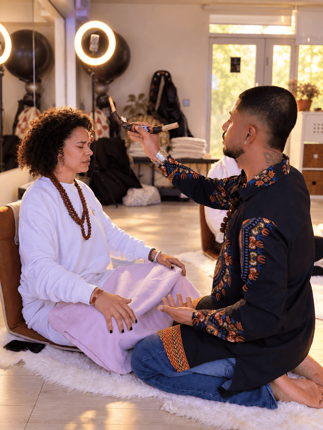 Facilitator performing a sound blessing over a seated participant